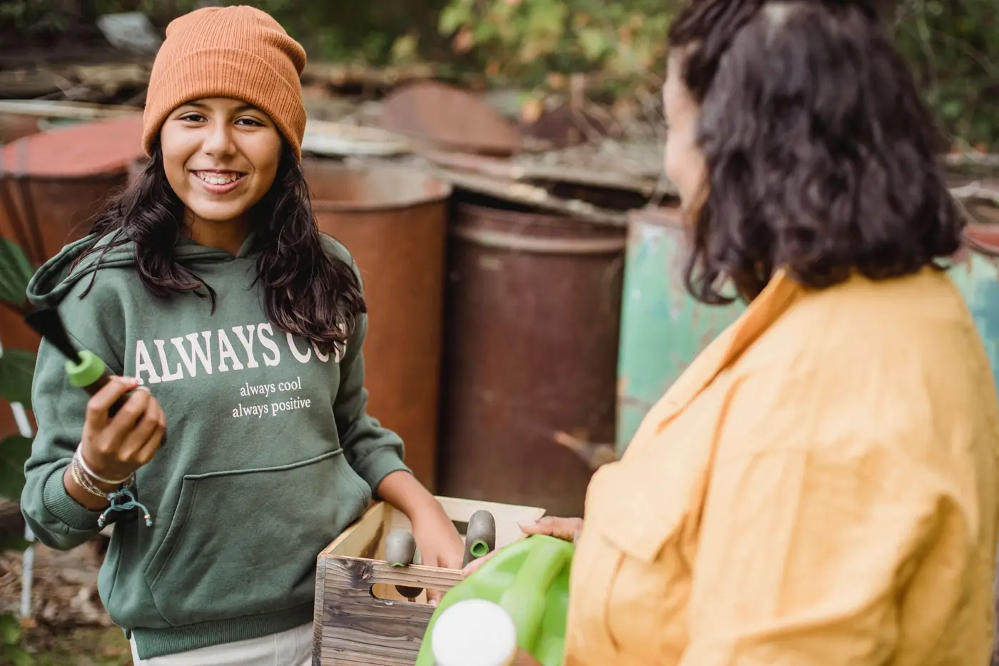 A smiling teenage girl gardening with a support worker
