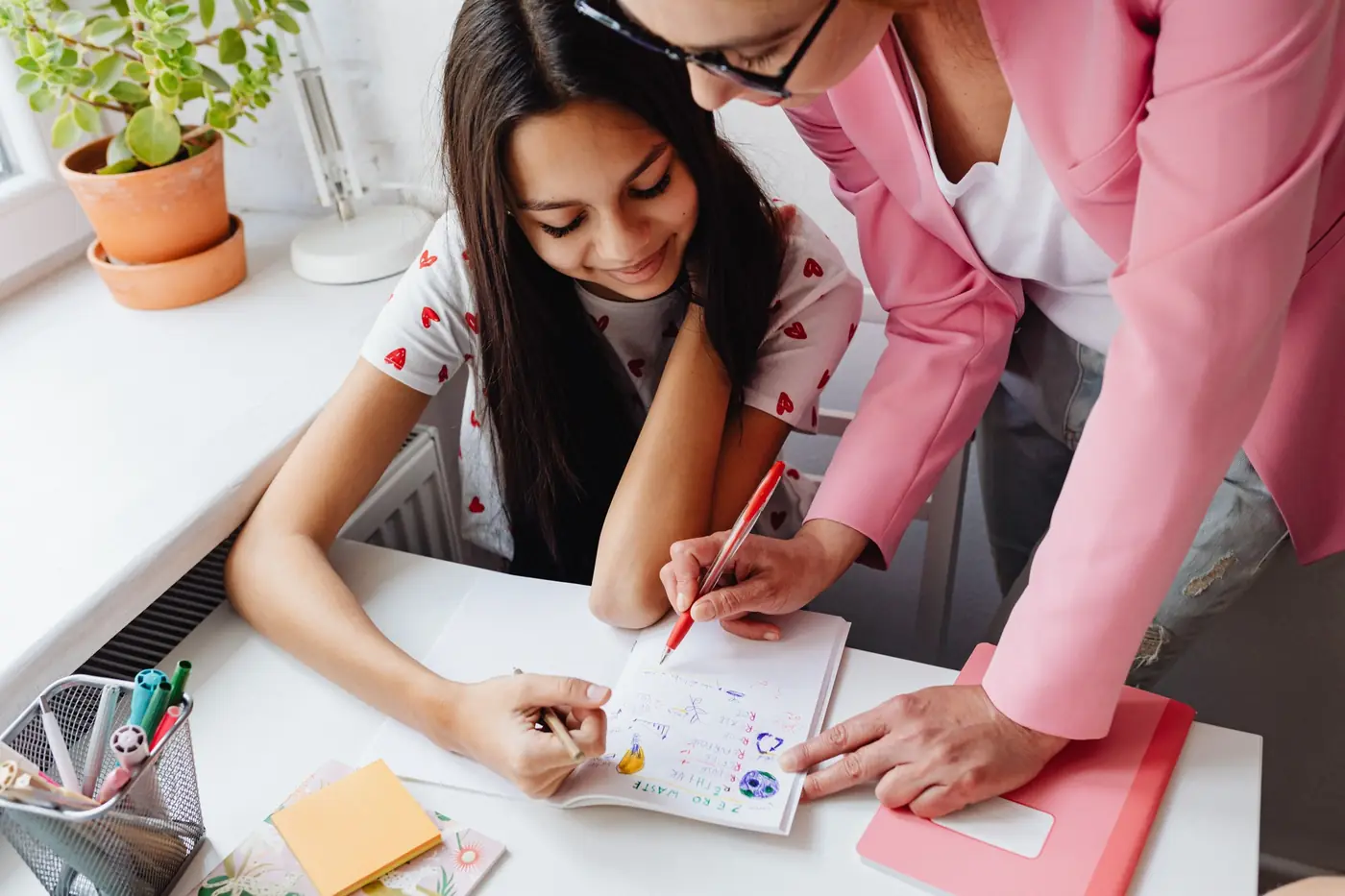A teenage girl doing her homework with a tutor encouraging her